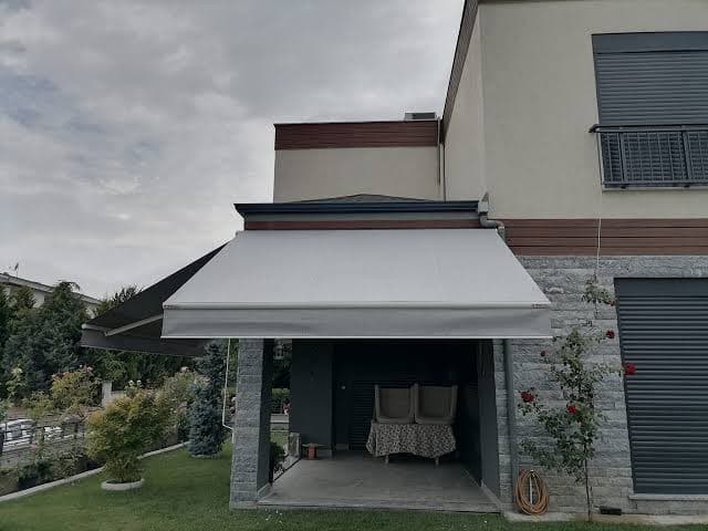 Balkona kolonsuz monte edilmiş mafsallı tente; kollar kumaşı öne iter