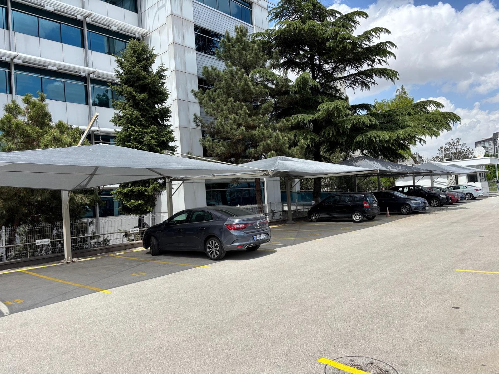 Konut önünde iskelet ve brandalı otopark çadırı; araç gölgede